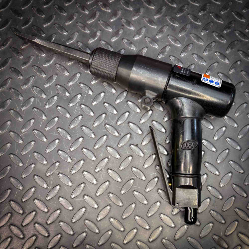 The Ingersoll Rand 180PG Pistol Grip Chisel Scaler displayed on a textured diamond-plate metal surface. The tool has a sleek black finish and an extended chisel head.