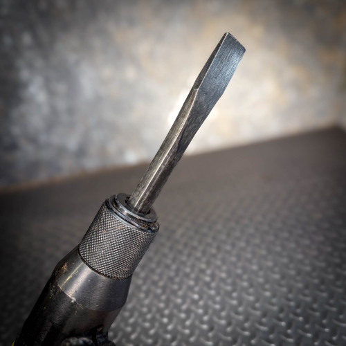 A detailed view of the chisel tip of the Ingersoll Rand 180PG Pistol Grip Chisel Scaler, highlighting its textured grip and flat-edged chisel attachment.