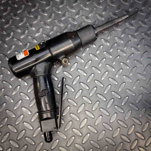 The Ingersoll Rand 180PG Pistol Grip Chisel Scaler resting on a textured diamond-plate surface, showing the full tool profile, including the ergonomic grip and chisel head.