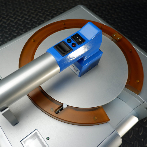 Close-up of the ProTec wafer handling chuck showing the blue and silver handheld device and the orange circular platform where the wafer is placed, highlighting the control buttons and indicator lights.