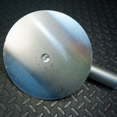 Bottom view of a metal circular component from the ProTec electrostatic wafer handling chuck racket, showing a smooth surface with small drilled holes and a central indentation.