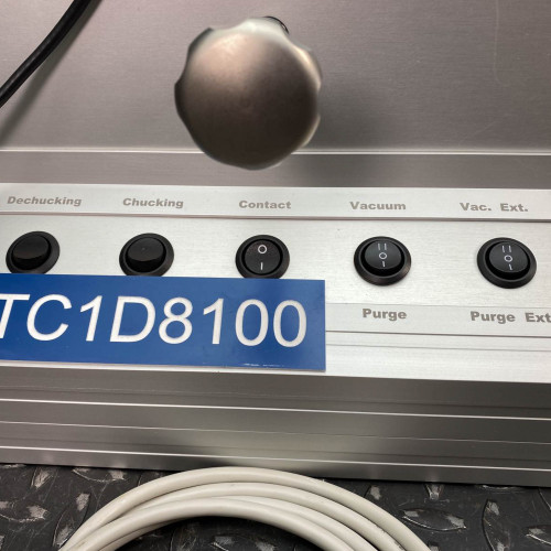 Close-up of the control panel of the ProTec electrostatic wafer handling chuck racket, highlighting buttons labeled de-chucking, chucking, contact, vacuum, vacuum exhaust, and purge, with a white power cord in the foreground.