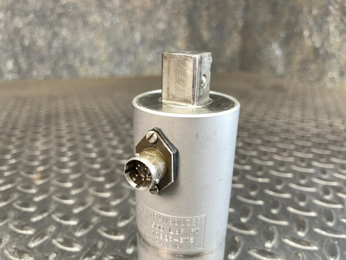 Close-up side view of the Norbar Torque Transducer showing the connector port and metal body with engraved specifications indicating a 500 LBF·FT capacity. The background surface is metallic and patterned.