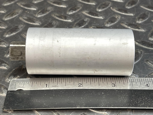Profile view of the Norbar Torque Transducer laying on its side, next to a ruler showing the length of the cylindrical device.