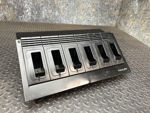 A Thales battery charger for MBITR tactical radios from Obtainium Science Surplus, positioned at an angle on a metal surface, showing all charging slots.