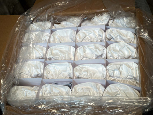 A box containing multiple neatly packed white protective PAPR hoods, each with a transparent face shield. PAPR Hood BE-10-20 available from Obtainium Science & Industry Surplus.