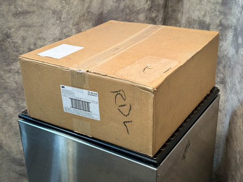 A sealed cardboard box with a shipping label, placed on top of a metal platform. PAPR Hood BE-10-20 available from Obtainium Science & Industry Surplus.
