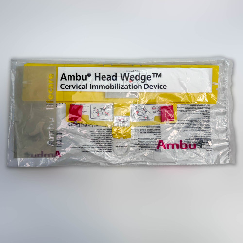 The image shows the Ambu Head Wedge cervical immobilization device packaged in a sealed, transparent plastic bag. The yellow components of the device and instructional diagrams are partially visible through the packaging. Labels on the device are clearly displayed, including the product name "Ambu Head Wedge Cervical Immobilization Device," which ensures that the contents are identified easily. This packaging is designed to maintain the device's sterility and readiness for emergency medical use.