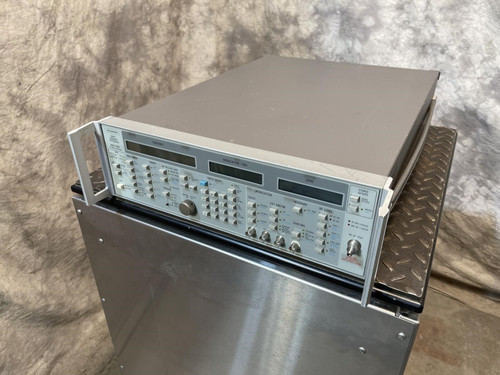 A Wiltron 6769B Synthesized Sweep Generator from Obtainium Science and Surplus, placed on a metal platform. The device features multiple dials and digital displays.