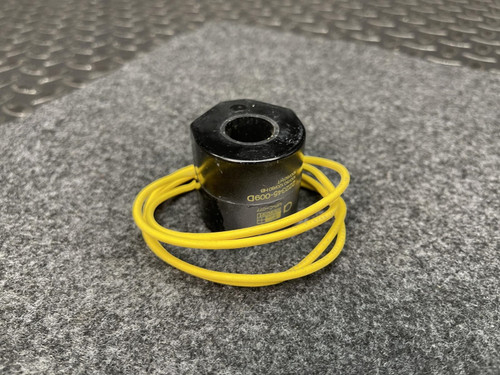 A close-up of the ASCO Replacement Coil 222345-009-D – 120V HB Series, with yellow wires coiled around it, resting on a gray fabric surface.