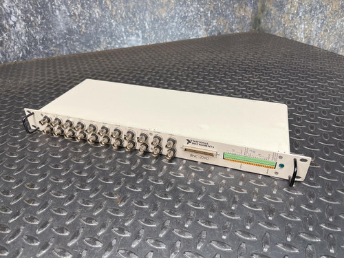 A National Instruments BNC-2090 terminal block with multiple BNC connectors, placed on a textured metal surface. This item is available from Obtainium Science & Industry Surplus.