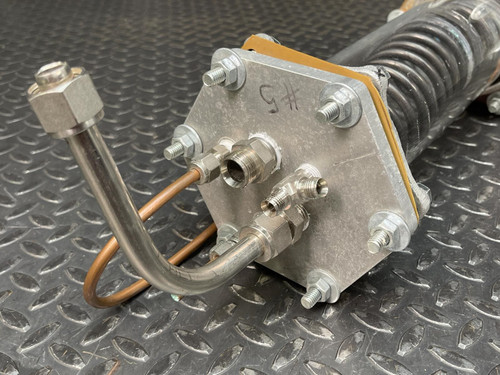 Close-up view of the custom-made vacuum/pressure chamber’s end plate from Obtainium Science and Surplus, showing the metal bolts, tubing, and fittings attached to the plate. The textured metal surface enhances the industrial look of the component.
