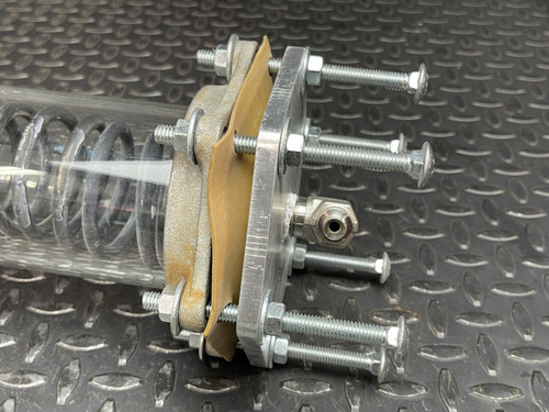 Side view of the custom-made vacuum/pressure chamber from Obtainium Science and Surplus, focusing on the end plate with bolts and connectors, highlighting the intricate design and assembly of this industrial piece.