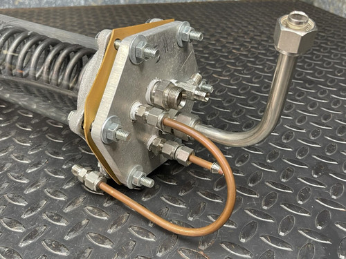 Close-up of the end plate of the Obtainium Science and Surplus custom-made vacuum/pressure chamber, showing multiple connectors and copper tubing. The metal bolts and rugged surface add to the industrial aesthetic of the component.