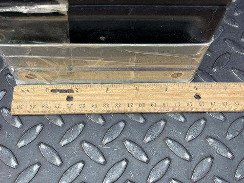 Close-up of a Nylatube Energy Chain Wireway section with a wooden ruler placed below it for scale, showing measurements in inches. The wireway is displayed on a textured metal surface, emphasizing its size and sturdy construction.