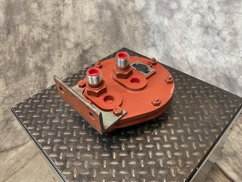 Side view of the Graham heat exchanger from Obtainium Science and Surplus, focusing on the flat, red metal end plate with two main ports and bolts. The component rests on a black textured surface.