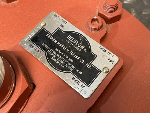 Close-up of the identification plate on the Graham heat exchanger from Obtainium Science and Surplus, showing manufacturing details such as model and serial number on a black and silver label attached to the red end plate.