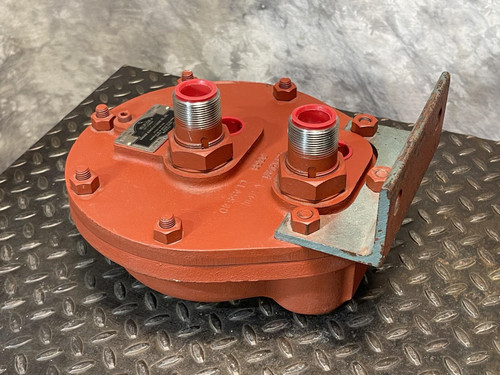 Angled view of the Graham heat exchanger from Obtainium Science and Surplus, showing the red metal body with two primary ports and multiple securing bolts around the plate. It rests on a black, textured surface for contrast.