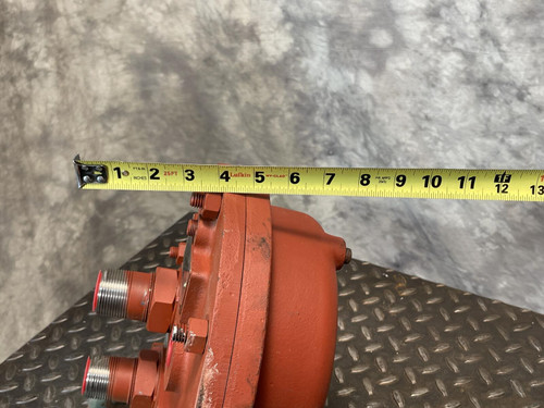 Side view of the Graham heat exchanger from Obtainium Science and Surplus with a yellow measuring tape placed horizontally along the red casing, showing its width. The ports and bolts on the end plate are visible against the metal background.
