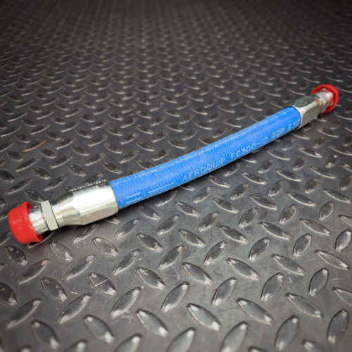 A blue Aeroquip FC300 hose with JIC hydraulic fittings from Obtainium Science and Surplus, lying on a black, textured metal surface. Both ends of the hose are capped with red protective covers.