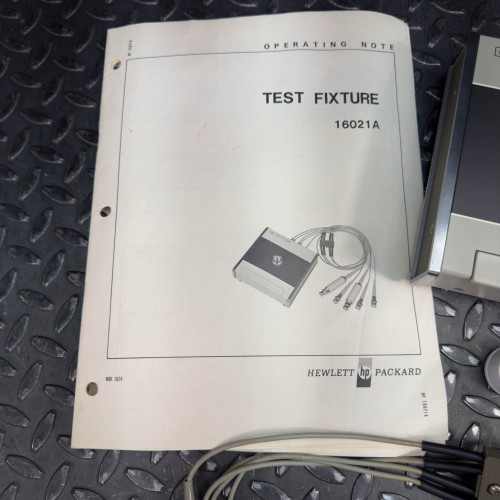 Operating manual for the Hewlett Packard 16021A Test Fixture, titled 'Test Fixture 16021A' with a diagram of the device on the cover.