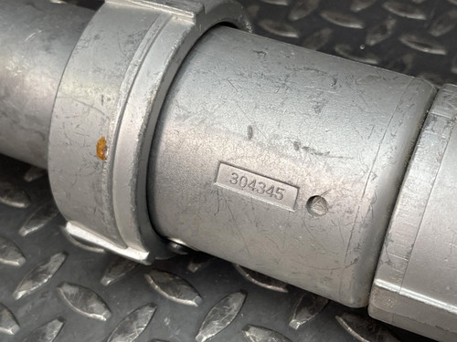 Close-up of the side of an Appleton 100A plug from Obtainium Science and Surplus, showing a part number engraved on its metallic surface, placed on a metal surface.