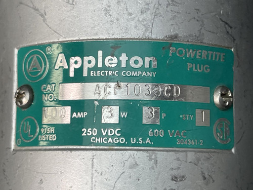 Close-up of the label on an Appleton 100A plug from Obtainium Science and Surplus, showing detailed information such as the manufacturer, voltage, and specifications, on a green background.