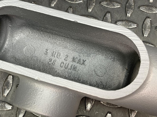 Close-up of the interior of a T conduit body from Obtainium Science and Surplus, showing the engraved text '4 NO.2 MAX 26 CU.IN'.