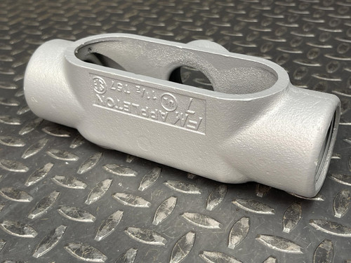 T conduit body from Obtainium Science and Surplus with embossed text, displayed on a metal surface showing its side profile.
