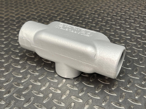 T conduit body from Obtainium Science and Surplus displayed on a metal surface, showing its side profile and threaded ports.