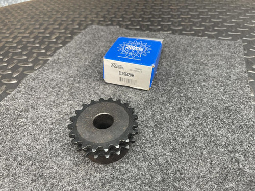 A Martin D35B20H double-row sprocket with 20 teeth displayed on a gray fabric surface. A blue product box labeled "Martin" with part details is also visible in the background. This sprocket is sourced from Obtainium Science and Surplus.
