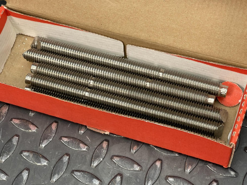 Hilti HAS-R 304 SS Anchor Rod - 1/2"x 6 1/2" from Obtainium Science and Surplus: An open red box containing multiple threaded rods neatly arranged inside, displayed on a textured metal surface.