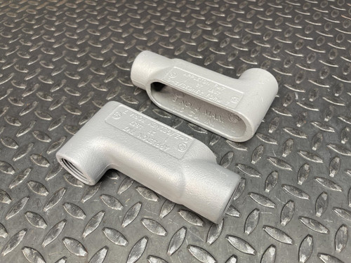 Two 1" Appleton LB Conduit Bodies from Obtainium Science and Surplus, displayed on a diamond plate surface.