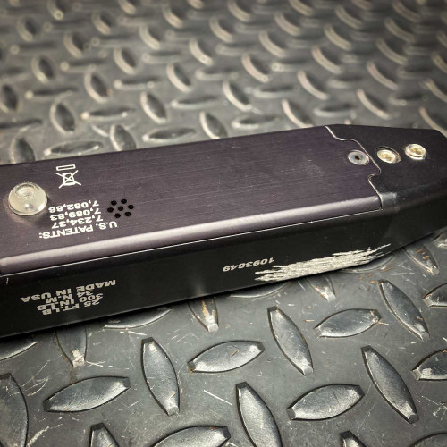 Close-up of the back panel on the Sturtevant Richmont Exacta 2 digital torque wrench. The panel features patent information, a small metal component, and several markings, indicating its high-quality construction and attention to detail. The tool rests on a textured metal surface, available from Obtainium Science & Industry Surplus.