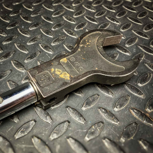 Close-up of the head attachment on the Sturtevant Richmont Exacta 2 digital torque wrench. The attachment shows signs of wear and is designed for precise torque applications, fitting securely onto the wrench's handle. The tool is placed on a textured metal surface, available from Obtainium Science & Industry Surplus.