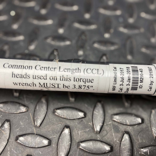 Close-up of the label on the handle of the Sturtevant Richmont Exacta 2 digital torque wrench. The label specifies that the common center length (CCL) heads used on this torque wrench must be 3.875 inches. This detail underscores the tool's precision requirements, set against a textured metal background, available from Obtainium Science & Industry Surplus.