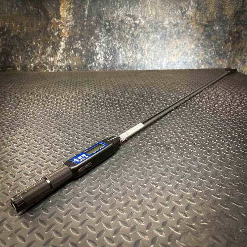 A digital torque wrench, specifically the Sturtevant Richmont Exacta 2 model, is displayed on a textured metal surface. The tool features a digital display and control buttons, with a long, slender handle designed for precision torque measurement, available from Obtainium Science & Industry Surplus.