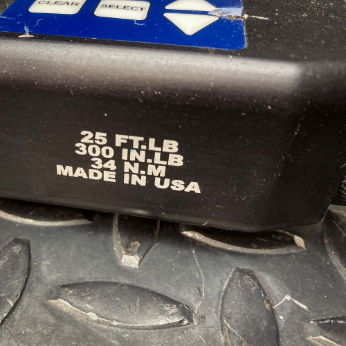 Close-up view of the Sturtevant Richmont Exacta 2 digital torque wrench showing its torque range specifications: 25 ft-lb, 300 in-lb, and 34 N·m. The text also indicates that the tool is made in the USA, emphasizing its precision and quality construction. The tool is set against a textured metal background, available from Obtainium Science & Industry Surplus.