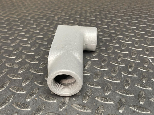 Angled side view of a 1" Appleton LB37 Conduit Body from Obtainium Science and Surplus on a diamond plate surface, showing the threaded opening.