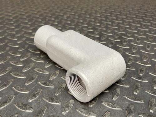 Side view of a 1" Appleton LB37 Conduit Body from Obtainium Science and Surplus on a diamond plate surface, with a wooden ruler placed next to it for scale.