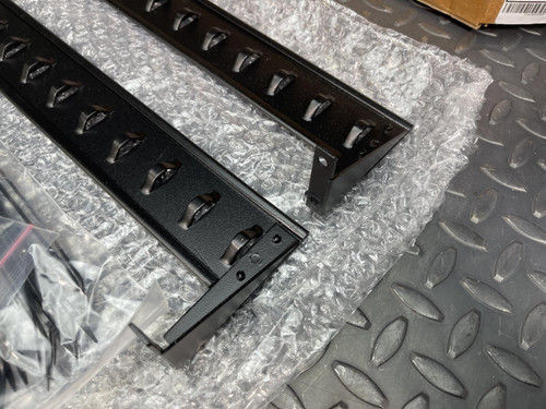 Close-up of two black metal mounting brackets with angled slots, part of the APC Basic PDU Accessory Kit from Obtainium Science and Surplus.