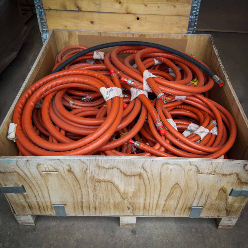 A large wooden crate filled with coiled orange hydraulic hoses for a Brokk remote demolition machine, available for sale from Obtainium Science & Industry Surplus.
