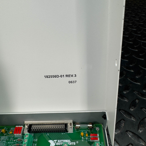 The image is a close-up view of the interior side panel of a National Instruments SCB-68 terminal block connector. It highlights the text "182510G-01 REV 3" and "0637" printed on the white panel. Below this, part of the green circuit board and connector port are visible, along with the National Instruments logo. The device is placed on a textured metal surface.