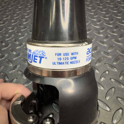 Task Force Tips TFT LX FoamJet firefighter foam-making attachment from Obtainium Science & Industry Surplus, showing the label indicating use with 10-125 GPM and the nozzle's metallic and plastic components.