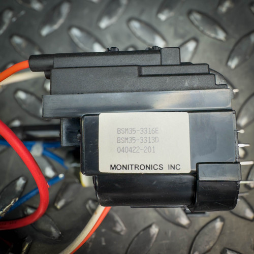 Close-up view of a vintage CRT monitor flyback transformer from Obtainium Science & Industry Surplus, highlighting the label with product details.