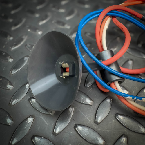 A cone-shaped part of a vintage CRT monitor flyback transformer from Obtainium Science & Industry Surplus, with red and blue wires coiled beside it.