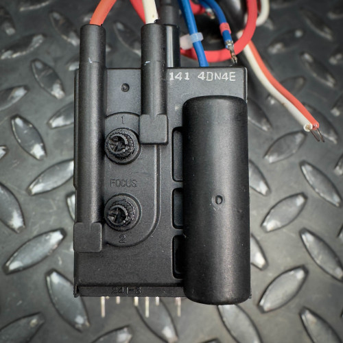 Back view of a vintage CRT monitor flyback transformer from Obtainium Science & Industry Surplus, showing its black casing and attached wires.