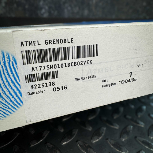 Side view of the ATMEL Biometric FingerChip development board kit box from the Obtainium Science Surplus Store, showing the product label with barcode and specifications.