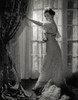 Bette Davis in a delicate white dress standing by the window by George Hurrell.