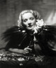 Gorgeous Marlene Dietrich portrait styled in a black feather cape where she holds a white rose. Shot by William Walling, Jr.